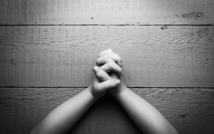 Child's hands folded together in prayer. Black and white photo
